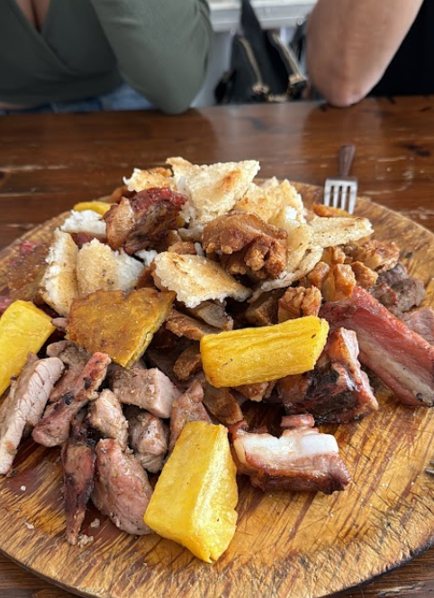 Tabla de madera con parrillada de carnes a la brasa, chicharrón, yuca frita y arepa