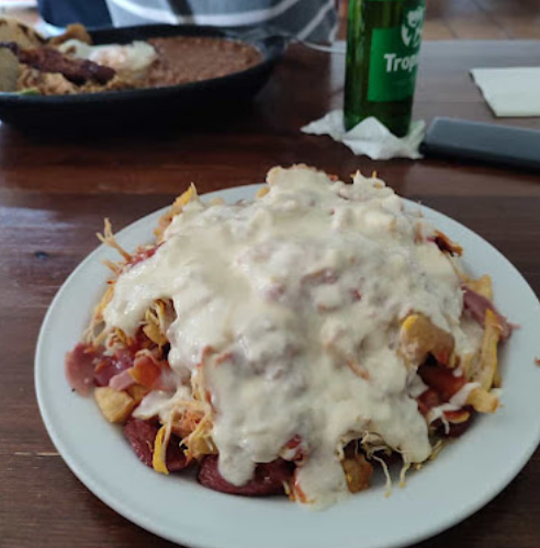 Plato de salchipapa con papas, salchicha, pollo mechado y queso fundido